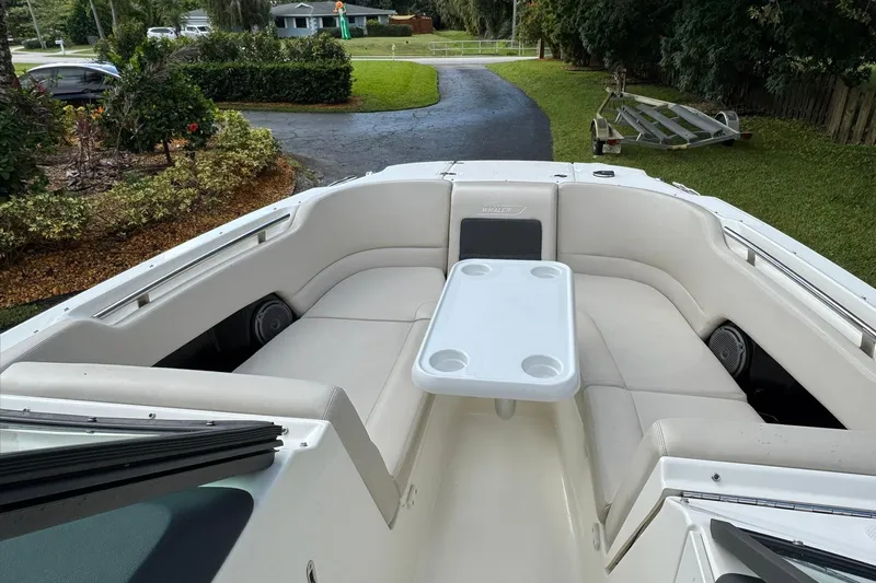  Yacht Photos Pics 2019 Boston Whaler 230 Vantage boat with cushioned seating and table, parked in driveway.