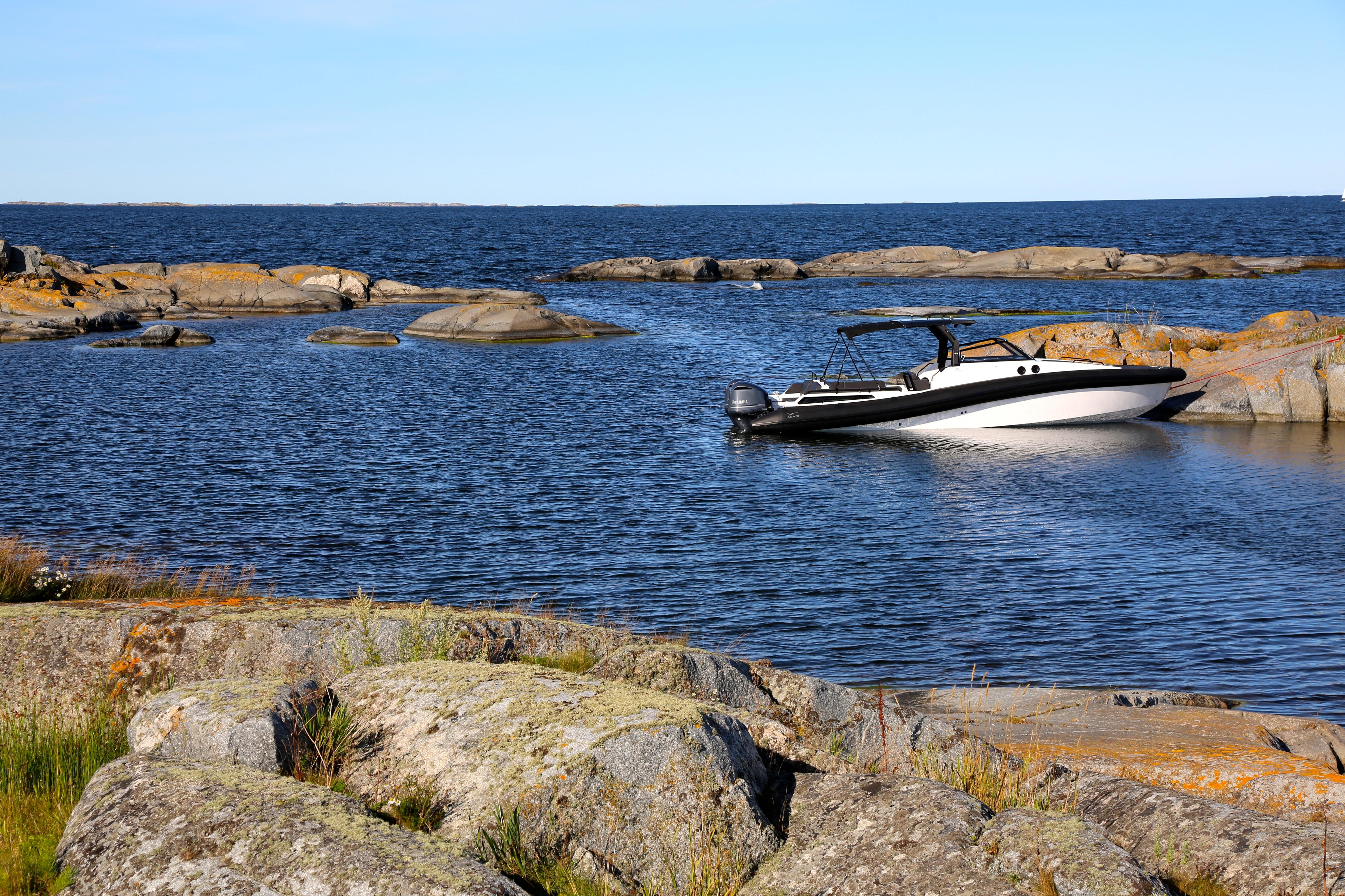 AGAPI 950 boat in rocky coastal waters, 2026 model, under clear blue sky.