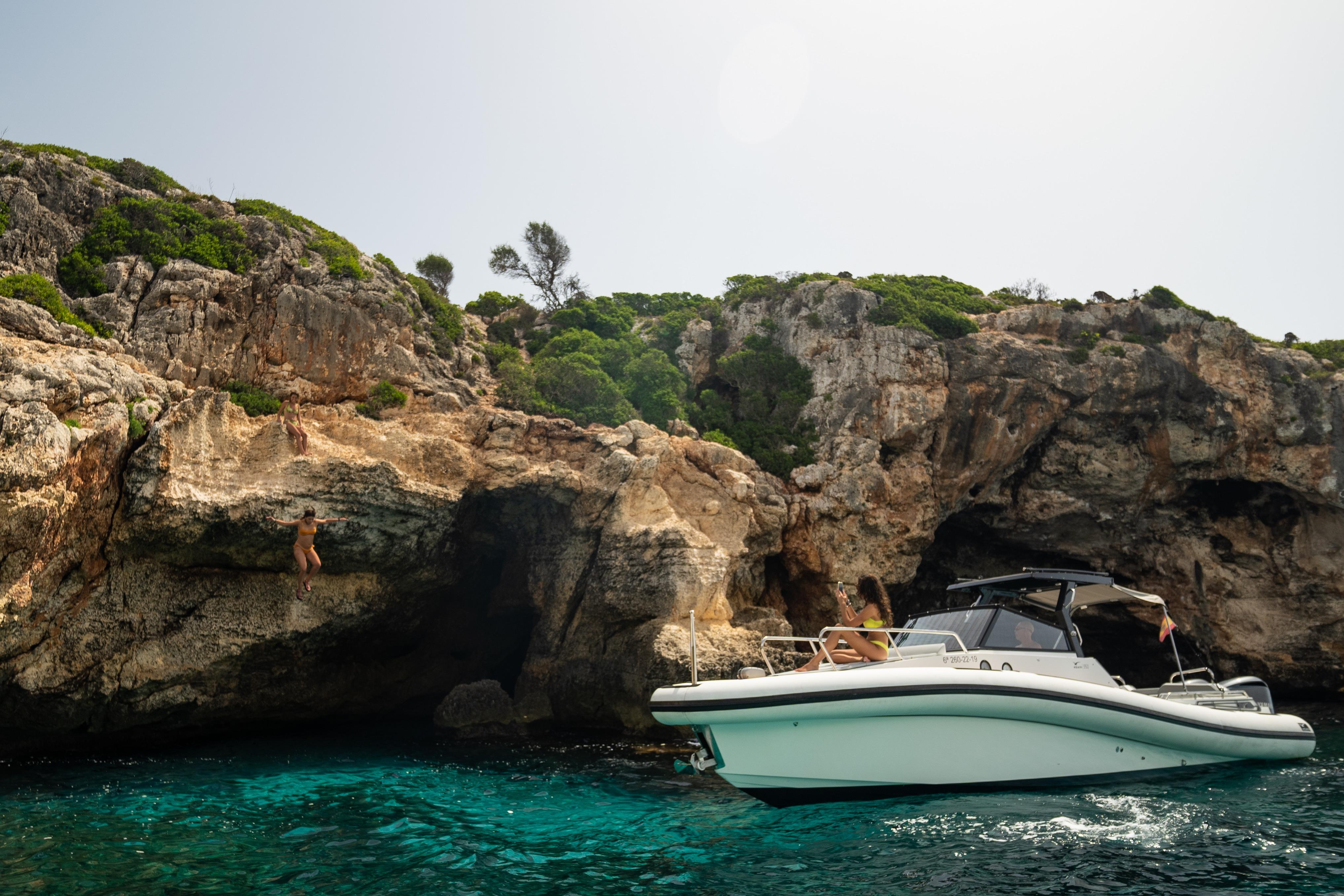 AGAPI 950 boat near rocky cliffs, clear turquoise water, 2026 model.
