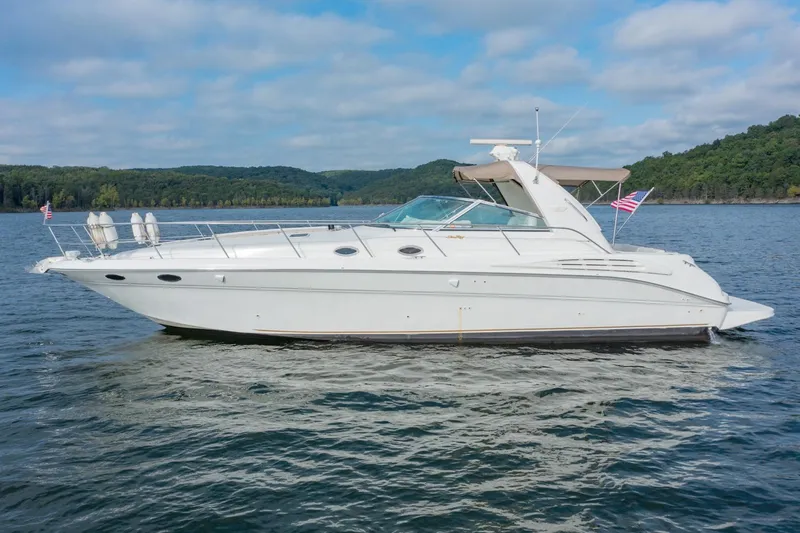 Just The Two Of Us Yacht Photos Pics 1997 Sea Ray 400 Sundancer yacht cruising on a scenic lake with forested hills.