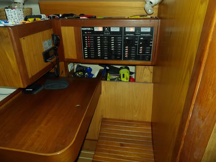 Summer Breeze Yacht Photos Pics Navigation station of a 2000 Hunter 460 sailboat with control panels and wooden cabinetry.