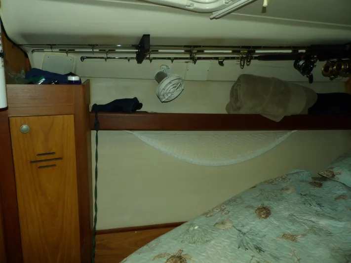 Summer Breeze Yacht Photos Pics 2000 Hunter 460 boat interior with storage shelf, fishing rods, and bedding.