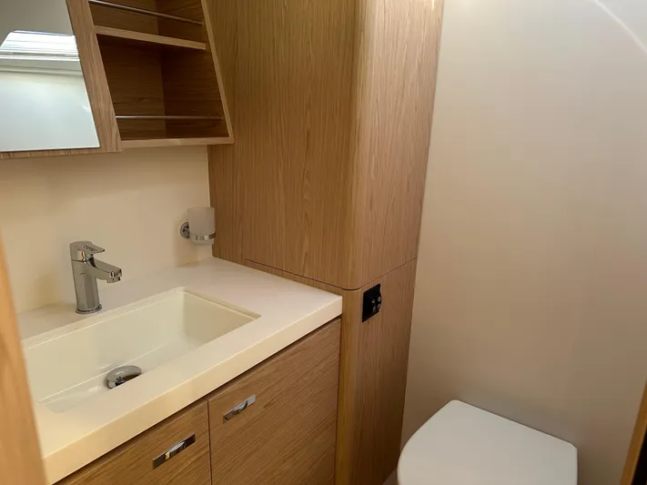  Yacht Photos Pics Modern bathroom in 2023 Beneteau First 53 yacht with wood cabinetry and sleek fixtures.