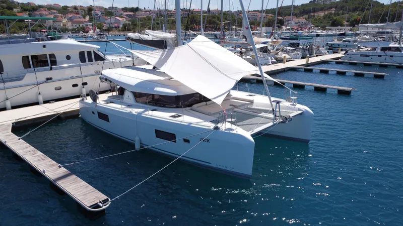  Yacht Photos Pics 2023 Lagoon 42 catamaran docked in a marina, featuring sleek design and spacious deck.
