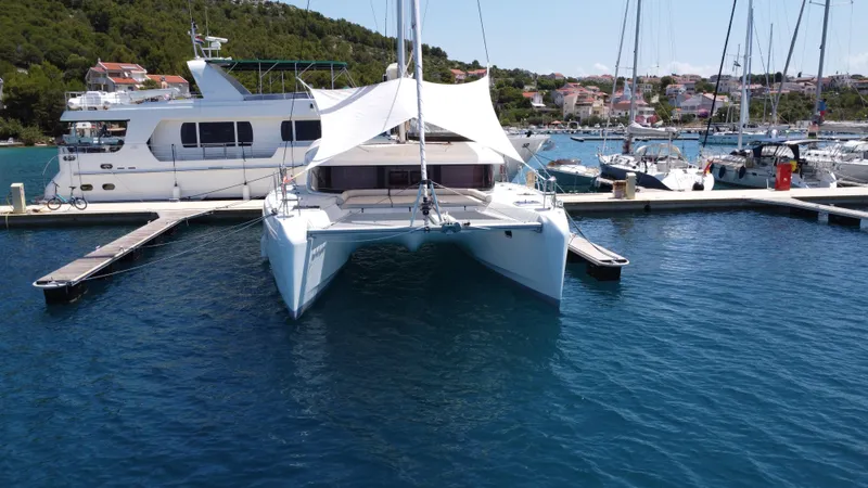  Yacht Photos Pics 2023 Lagoon 42 catamaran docked in a marina, surrounded by other boats.