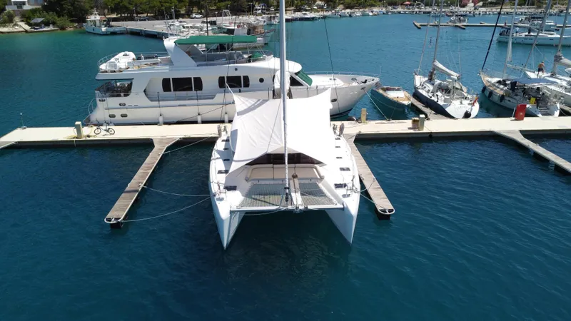  Yacht Photos Pics 2023 Lagoon 42 catamaran docked at marina, surrounded by other boats.