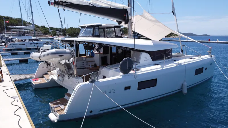  Yacht Photos Pics 2023 Lagoon 42 catamaran docked at marina, featuring modern design and spacious deck.