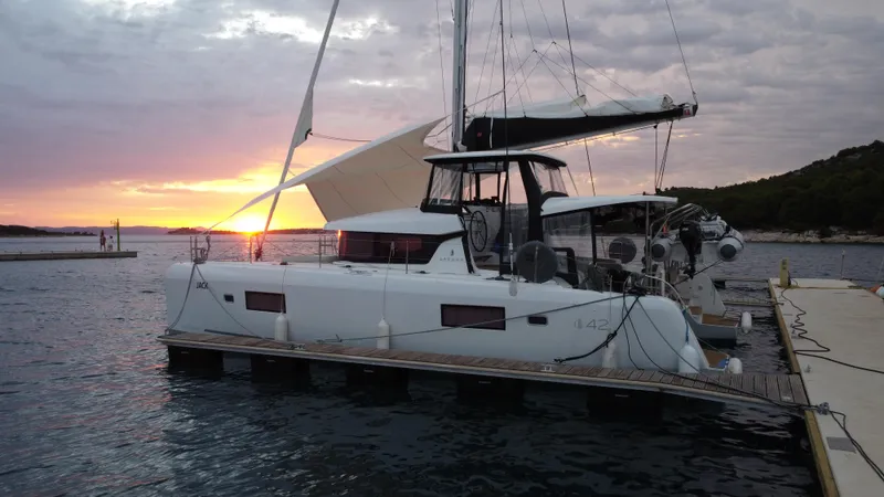  Yacht Photos Pics 2023 Lagoon 42 catamaran docked at sunset, with scenic ocean view.