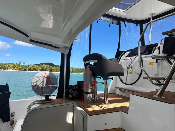  Yacht Photos Pics 2023 Lagoon 42 yacht interior with steering wheel, ocean view, and tropical island background.