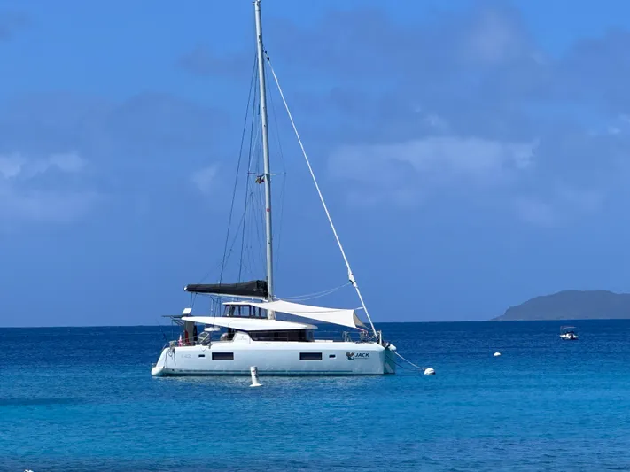  Yacht Photos Pics 2023 Lagoon 42 catamaran anchored in clear blue ocean waters.