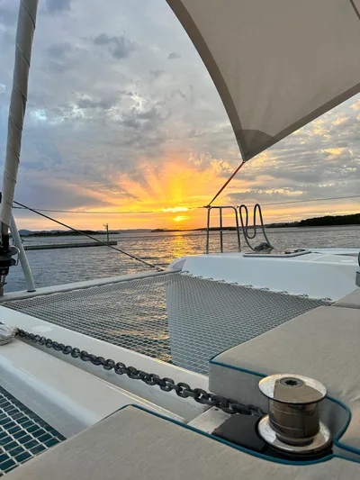  Yacht Photos Pics 2023 Lagoon 42 catamaran at sunset, with vibrant sky and calm waters.
