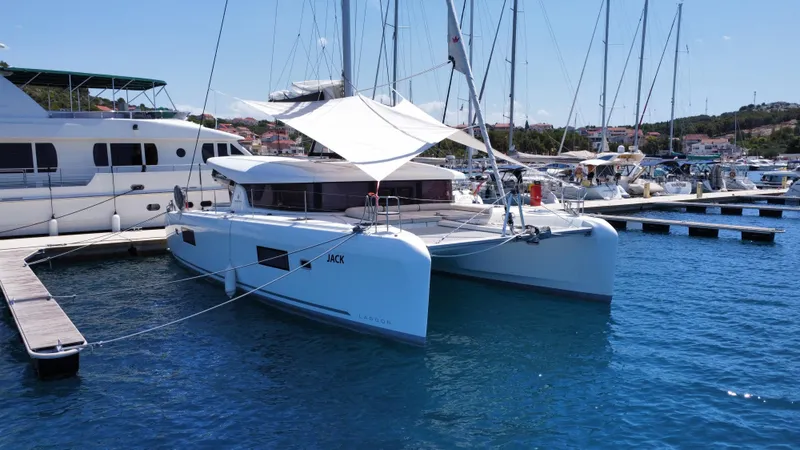  Yacht Photos Pics 2023 Lagoon 42 catamaran docked at marina, sunny day, clear blue water.