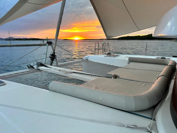  Yacht Photos Pics 2023 Lagoon 42 catamaran at sunset, featuring spacious deck and serene ocean view.