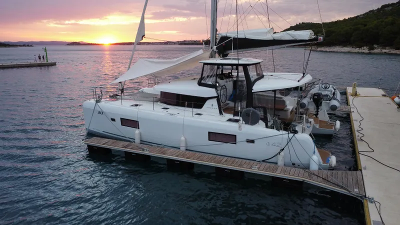  Yacht Photos Pics 2023 Lagoon 42 catamaran docked at sunset, serene waters, scenic backdrop.