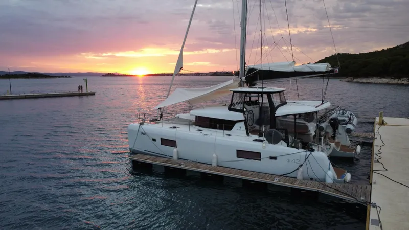 Yacht Photos Pics 2023 Lagoon 42 catamaran docked at sunset, serene waterfront view.
