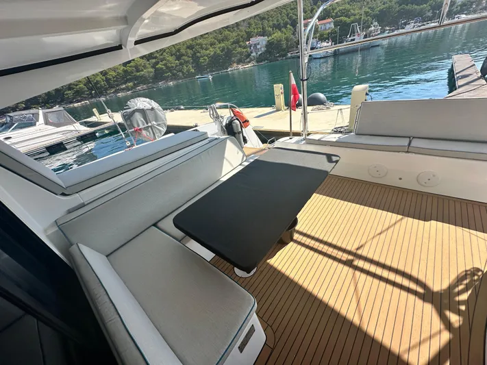  Yacht Photos Pics 2023 Lagoon 42 yacht deck with seating, table, and scenic marina view.