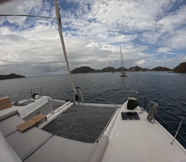  Yacht Photos Pics 2023 Lagoon 42 catamaran on calm sea with scenic island backdrop.