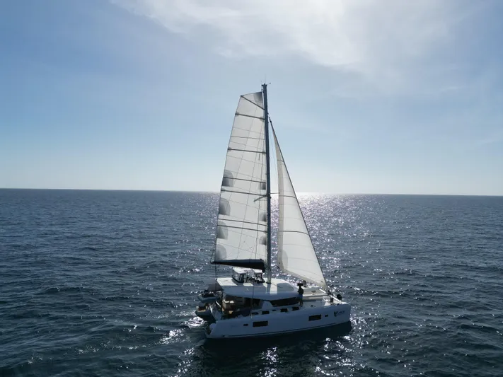  Yacht Photos Pics 2023 Lagoon 42 sailing catamaran on open sea under clear sky.
