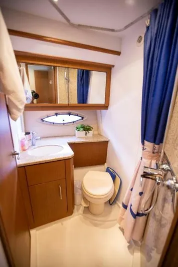 Tropical Life Yacht Photos Pics 2012 Carver Sojourn bathroom with wooden cabinetry, mirror, sink, toilet, and blue shower curtain.