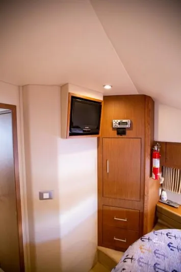 Tropical Life Yacht Photos Pics Interior of 2012 Carver Sojourn yacht with TV, wooden cabinets, and nautical-themed bedding.