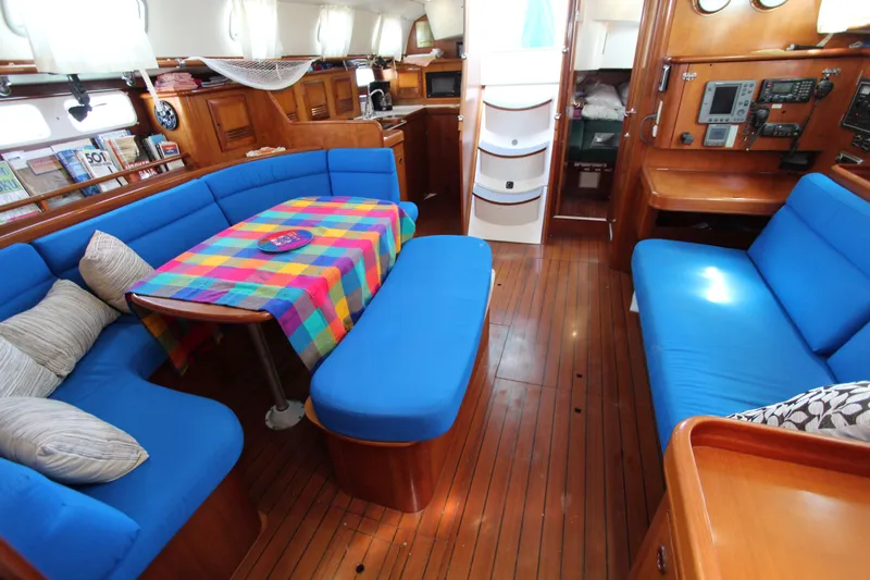 Oya Yacht Photos Pics Interior of 2001 Beneteau Oceanis 461 yacht with blue seating and colorful tablecloth.