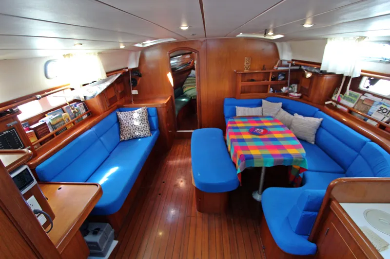 Oya Yacht Photos Pics Interior of 2001 Beneteau Oceanis 461 yacht with blue seating and colorful tablecloth.