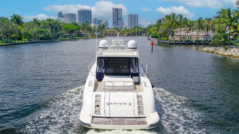 Gabriela G Yacht Photos Pics Luxury 2001 Mangusta 72 yacht cruising on a scenic waterway with city skyline backdrop.