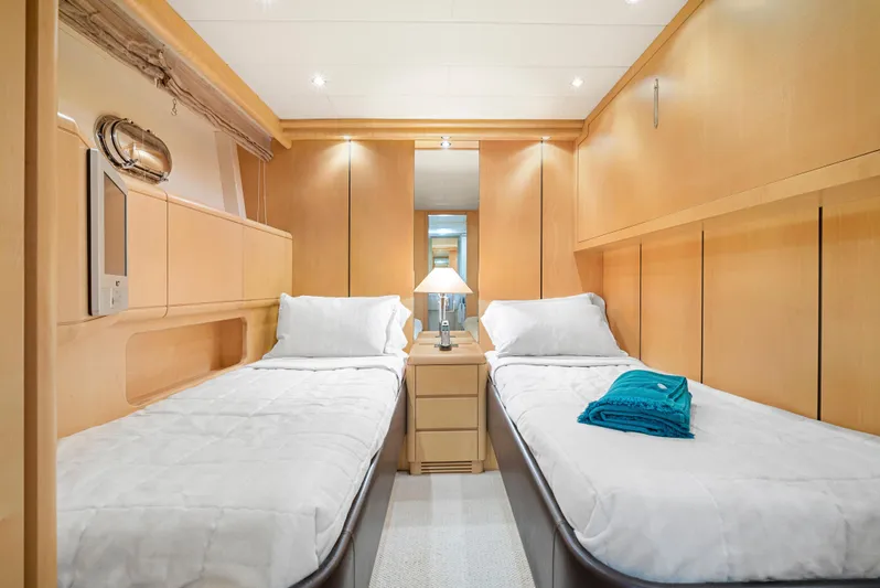 Gabriela G Yacht Photos Pics Luxurious twin cabin interior on 2001 Mangusta 72 yacht, featuring modern wood paneling and cozy bedding.