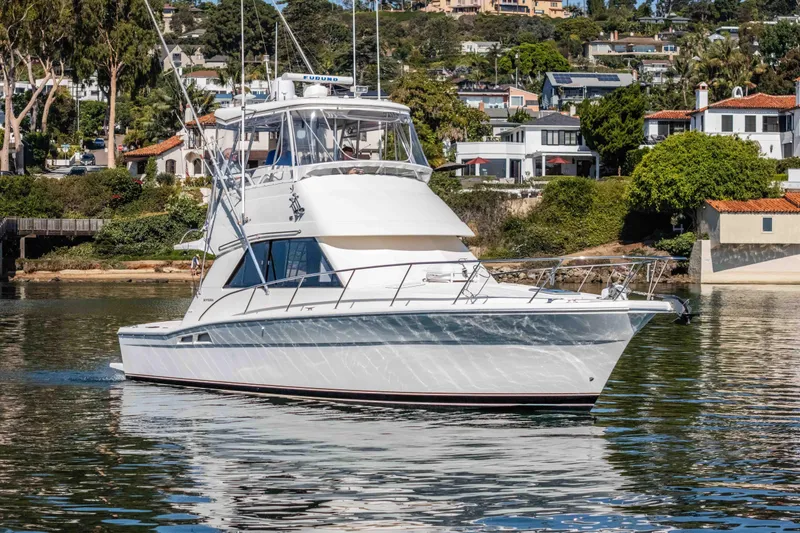 Sunny 1 Yacht Photos Pics 2001 Riviera 36 Flybridge yacht cruising near scenic waterfront homes.