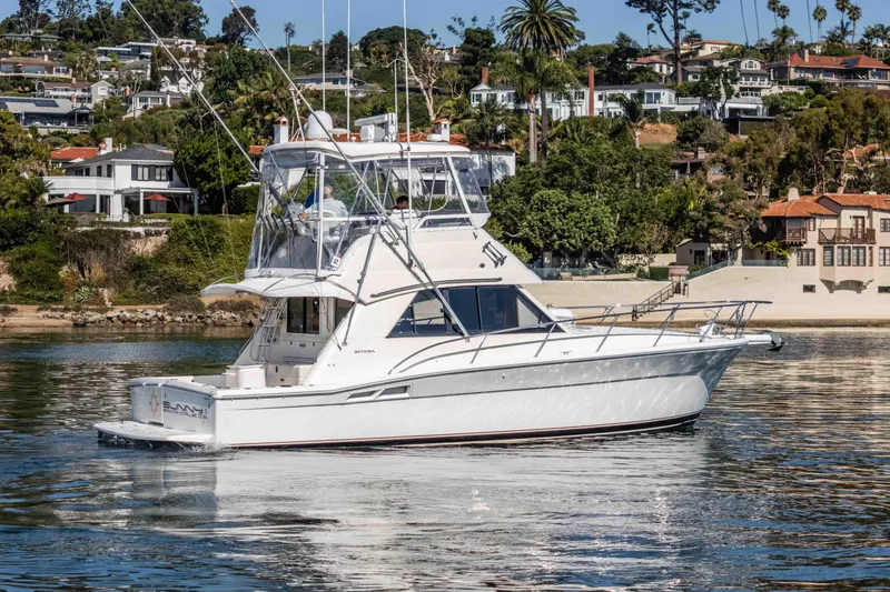 Sunny 1 Yacht Photos Pics 2001 Riviera 36 Flybridge yacht on calm water near coastal homes.