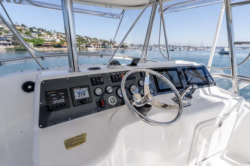 Sunny 1 Yacht Photos Pics Helm of 2001 Riviera 36 Flybridge yacht with modern navigation instruments and scenic marina view.