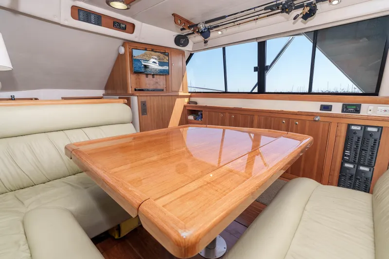 Sunny 1 Yacht Photos Pics Interior of 2001 Riviera 36 Flybridge yacht with wooden table and leather seating.