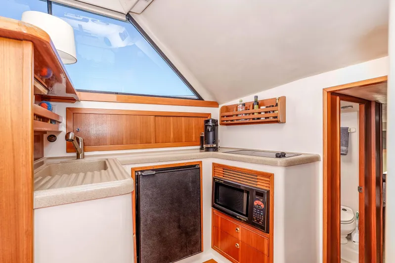 Sunny 1 Yacht Photos Pics 2001 Riviera 36 Flybridge yacht kitchen with sink, microwave, and wooden cabinetry.
