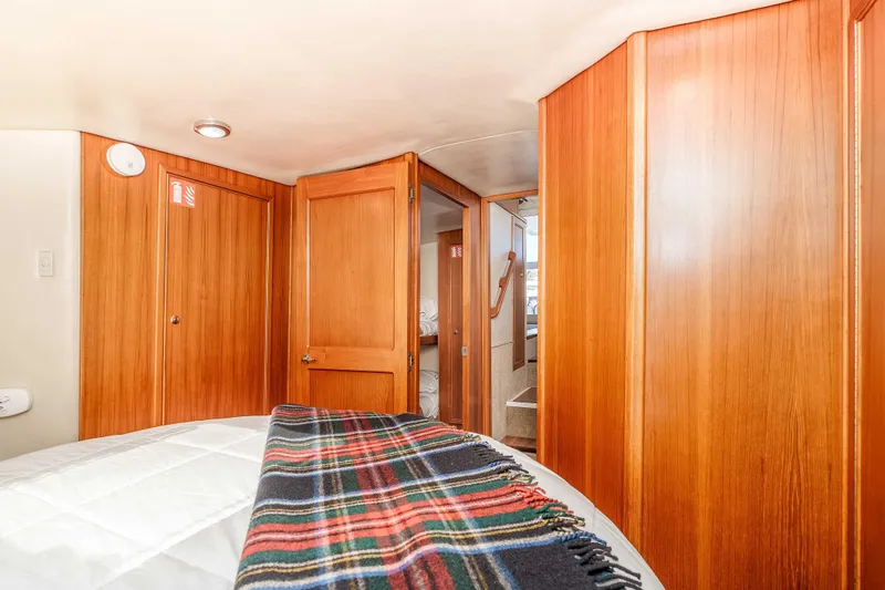 Sunny 1 Yacht Photos Pics Interior of 2001 Riviera 36 Flybridge yacht with wooden paneling and cozy bedding.