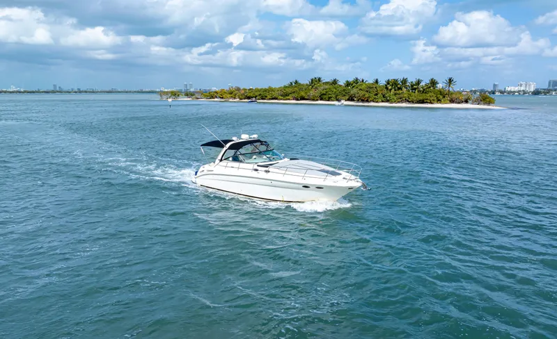 Genesis Yacht Photos Pics 2003 Sea Ray 380 Sundancer cruising near a tropical island under a partly cloudy sky.