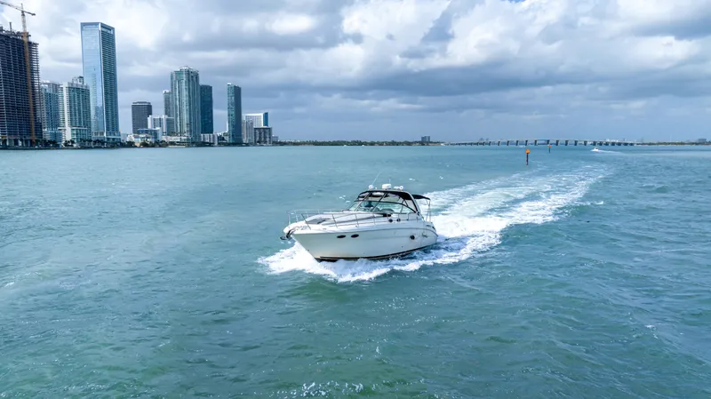 Genesis Yacht Photos Pics 2003 Sea Ray 380 Sundancer cruising near city skyline under cloudy skies.