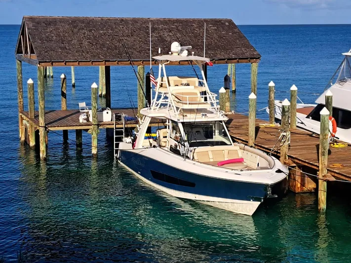 The Reel Deal Yacht Photos Pics 2016 Boston Whaler 420 Outrage docked at a wooden pier on clear blue water.