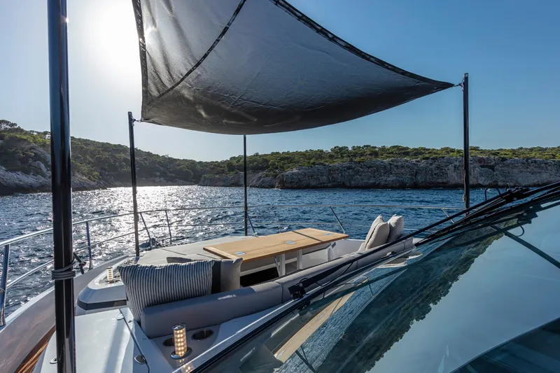 Bahari Yacht Photos Pics Luxurious 2020 Pearl 62 yacht with shaded deck, scenic coastal view.