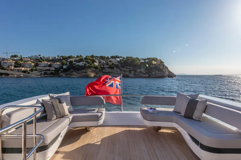 Bahari Yacht Photos Pics Luxurious Pearl 62 yacht deck with scenic ocean view, 2020 model, featuring comfortable seating and a flag.