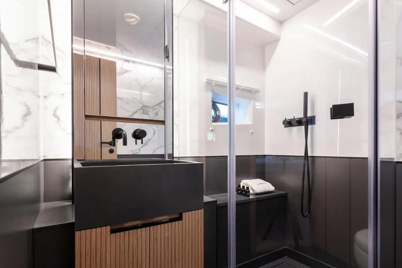 Bahari Yacht Photos Pics Modern yacht bathroom with sleek black fixtures, wood accents, and marble walls, Pearl 62 model 2020.