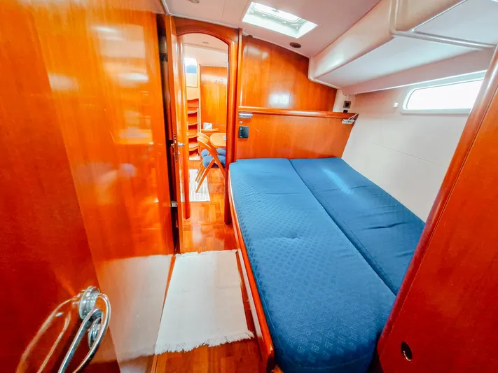  Yacht Photos Pics Luxurious cabin interior of 2004 Beneteau 57 yacht with wooden finish and blue bedding.