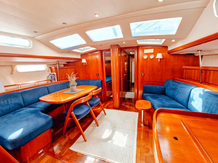  Yacht Photos Pics Luxurious interior of 2004 Beneteau 57 yacht with elegant wood finish and blue seating.