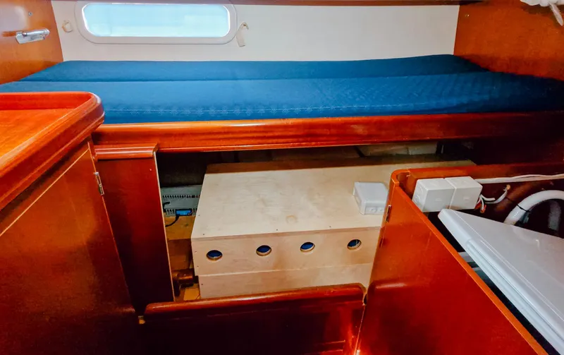  Yacht Photos Pics Interior cabin of a 2004 Beneteau 57 yacht with wooden furnishings and a blue mattress.