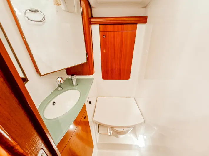  Yacht Photos Pics 2004 Beneteau 57 yacht bathroom with sink, mirror, and wooden cabinetry.