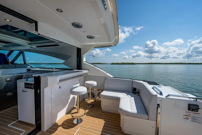 Legacy Yacht Photos Pics Luxurious 2022 Formula 500 Super Sport Crossover yacht interior with seating and bar, overlooking serene waters.