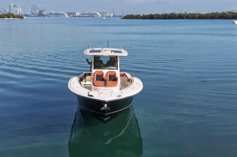  Yacht Photos Pics 2019 Scout 355 LXF boat cruising on calm waters with city skyline in background.
