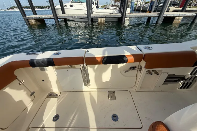  Yacht Photos Pics 2019 Scout 355 LXF boat interior near dock, featuring seating and water view.