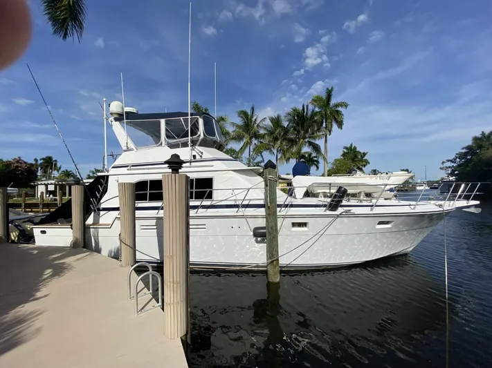 The Jolly Rogers Yacht Photos Pics 1987 Hi-Star Sportfish yacht docked at a marina with palm trees in the background.