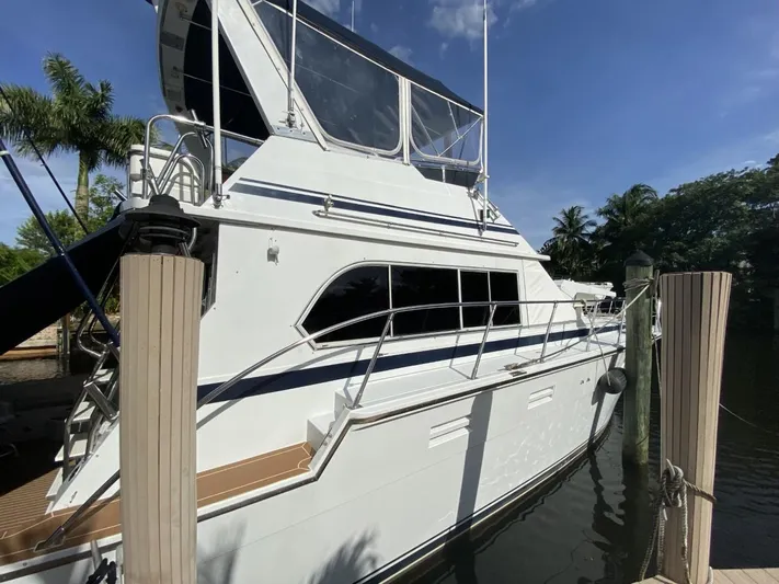 The Jolly Rogers Yacht Photos Pics 1987 Hi-Star Sportfish yacht docked, side view with clear blue sky and palm trees.