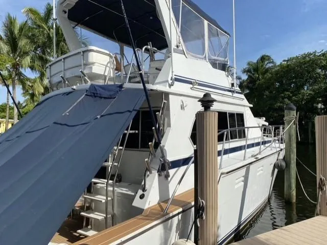 The Jolly Rogers Yacht Photos Pics 1987 Hi-Star Sportfish yacht docked at marina with blue canopy.